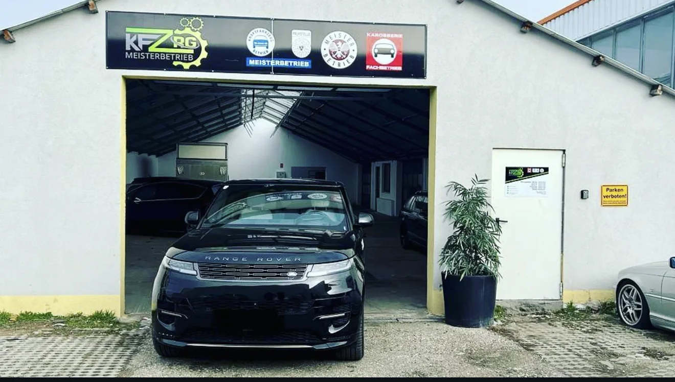 Werkstatt von KFZ RG Meisterbetrieb in Hagenbrunn – Range Rover in der Halle, Banner mit Logo und den Zertifizierungen Kraftfahrzeug-Betrieb, Prüfstelle, Meisterbetrieb und Karosserie-Fachbetrieb